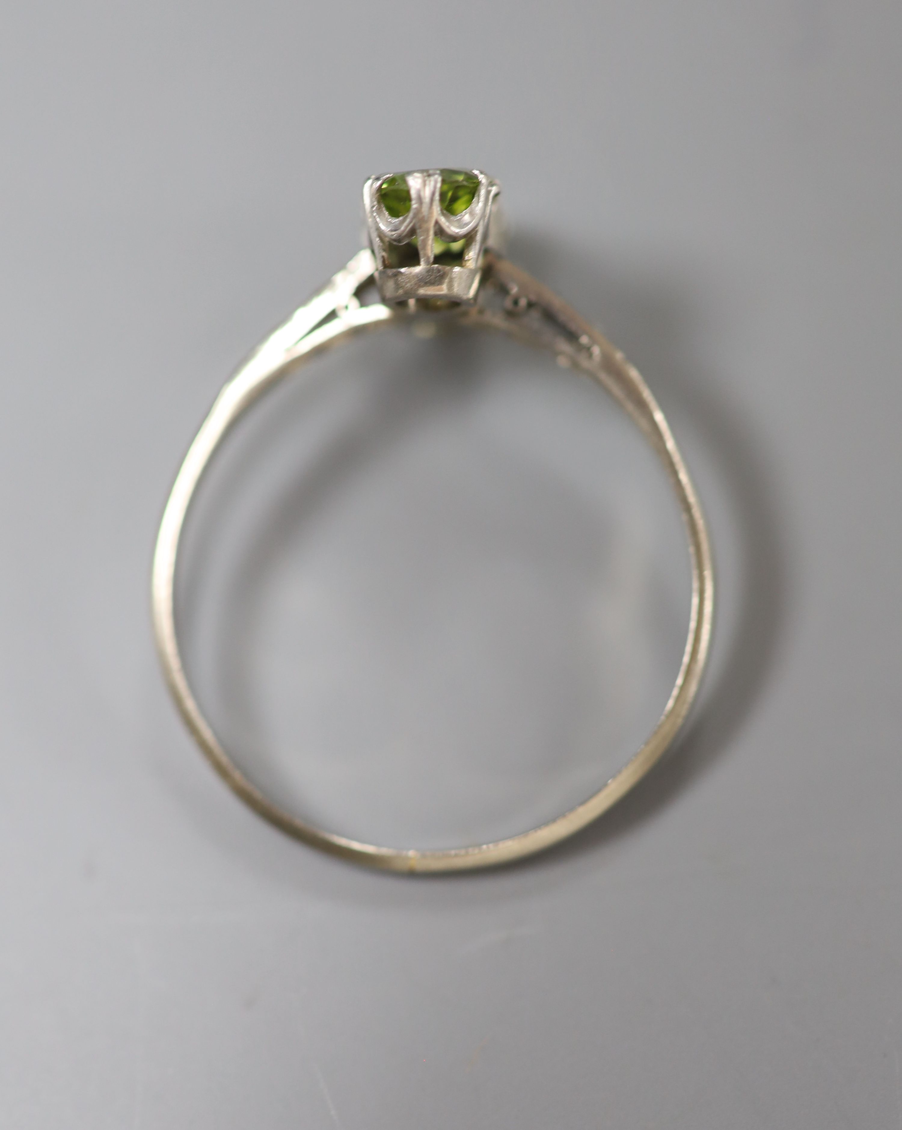 An 18ct and plat, two stone peridot crossover ring, with diamond set shoulders, size W, gross 2.7 grams.